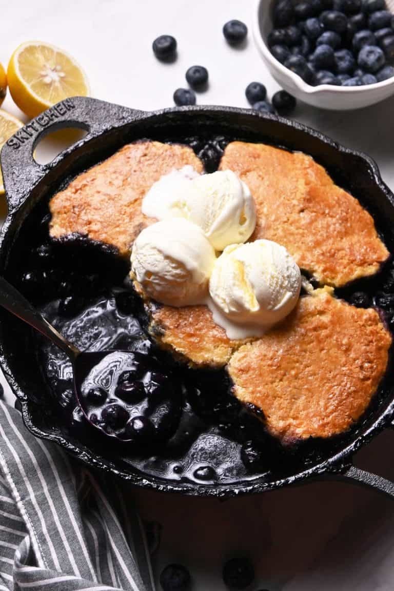 blueberry cobbler in a skillet with vanilla ice cream